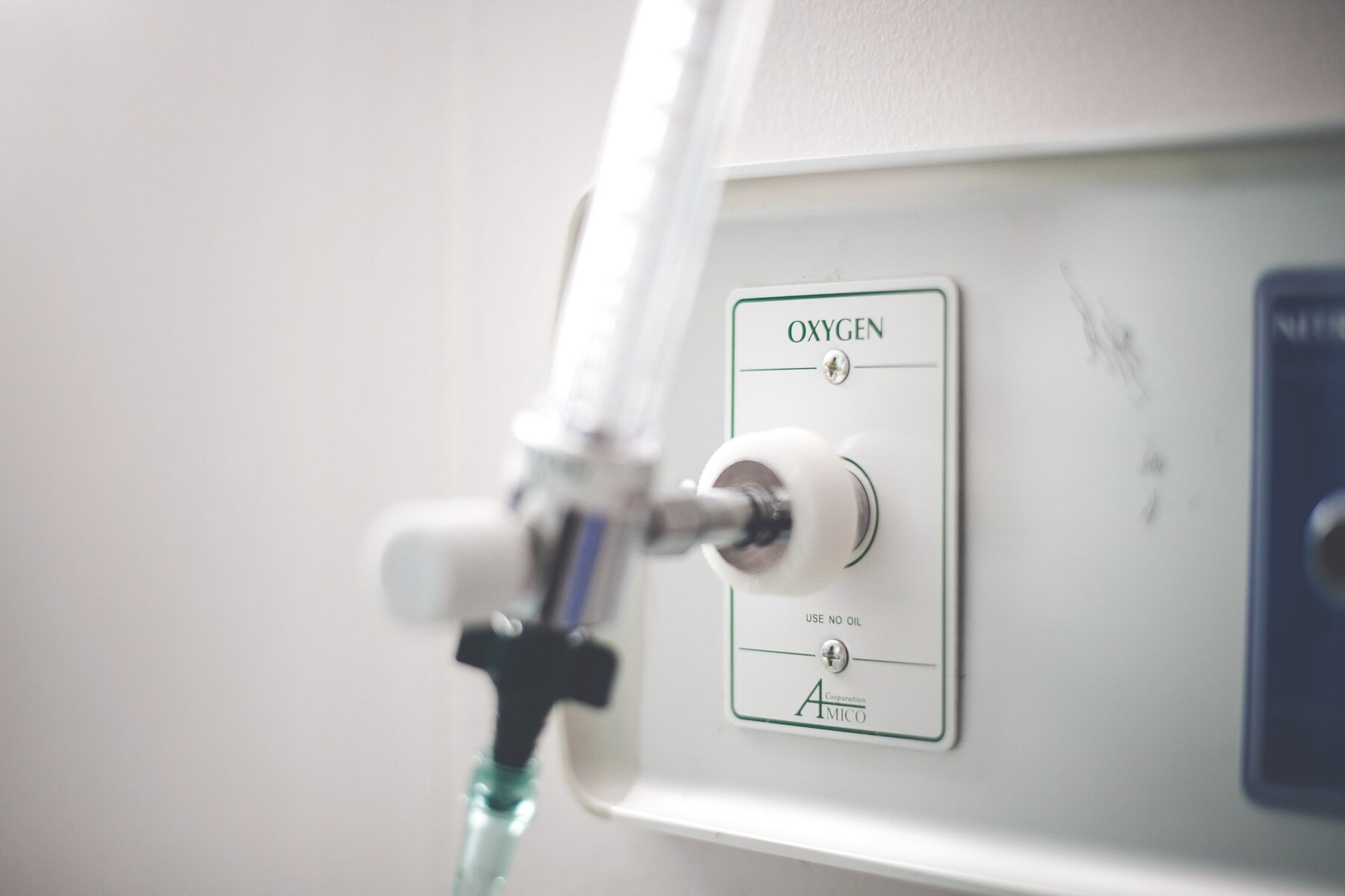A wall-mounted oxygen outlet with a flowmeter and humidifier connected to it.